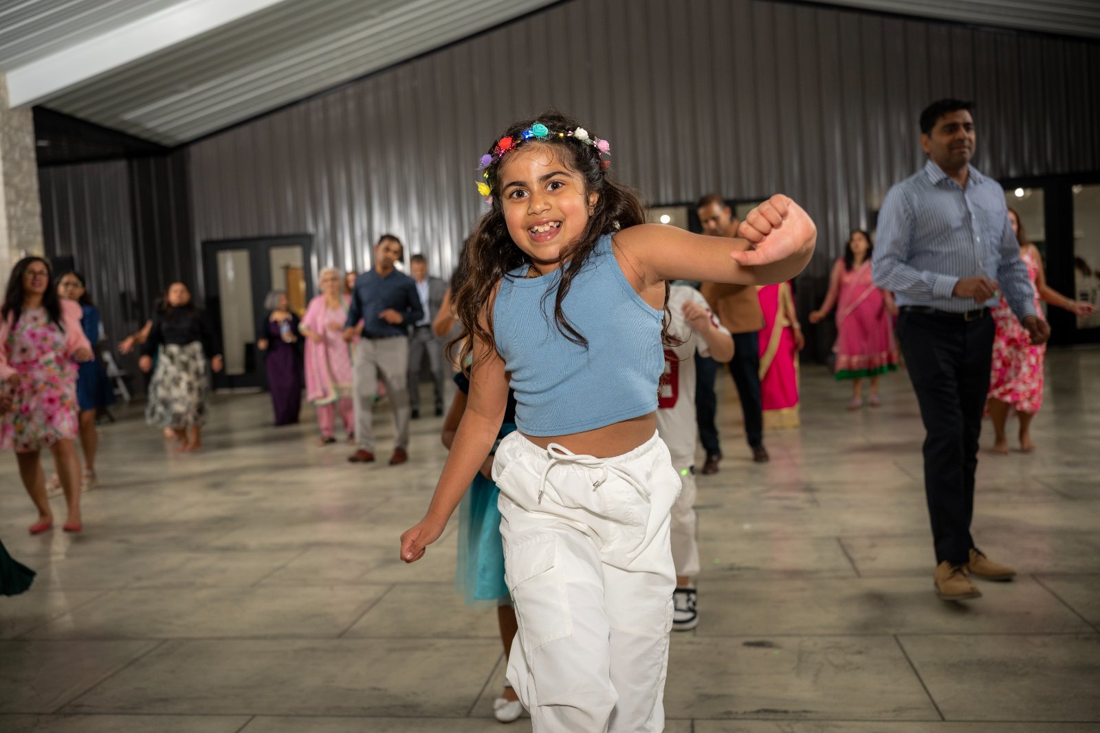 Child dancing joyfully during an indoor event celebration, surrounded by family and guests, captured by Zan Visuals as part of professional event photography coverage.