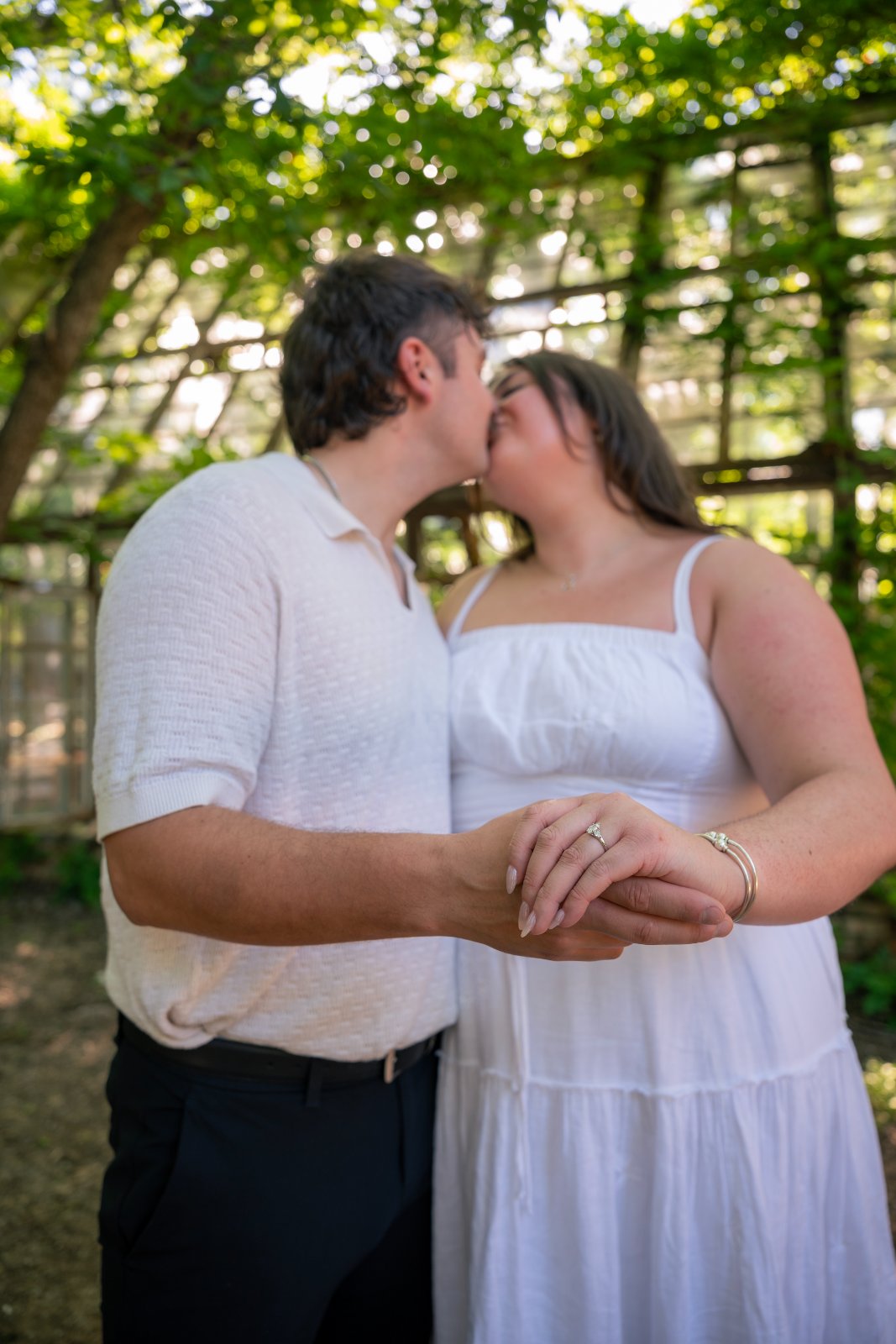 Romantic proposal moment showing a couple holding hands in a sunlit garden setting — taken by Zan Visuals.
