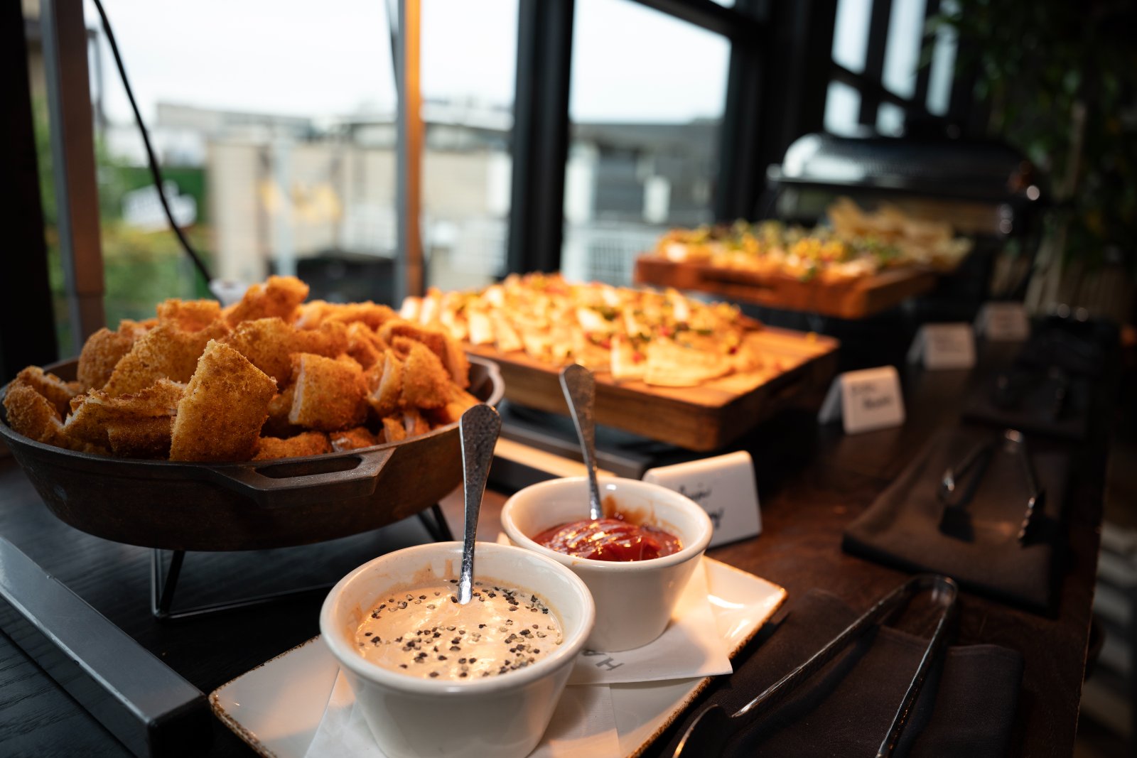 Buffet food setup at the Brohan Real Estate event inside Haywire, featuring appetizers and dipping sauces — photographed by Zan Visuals.
