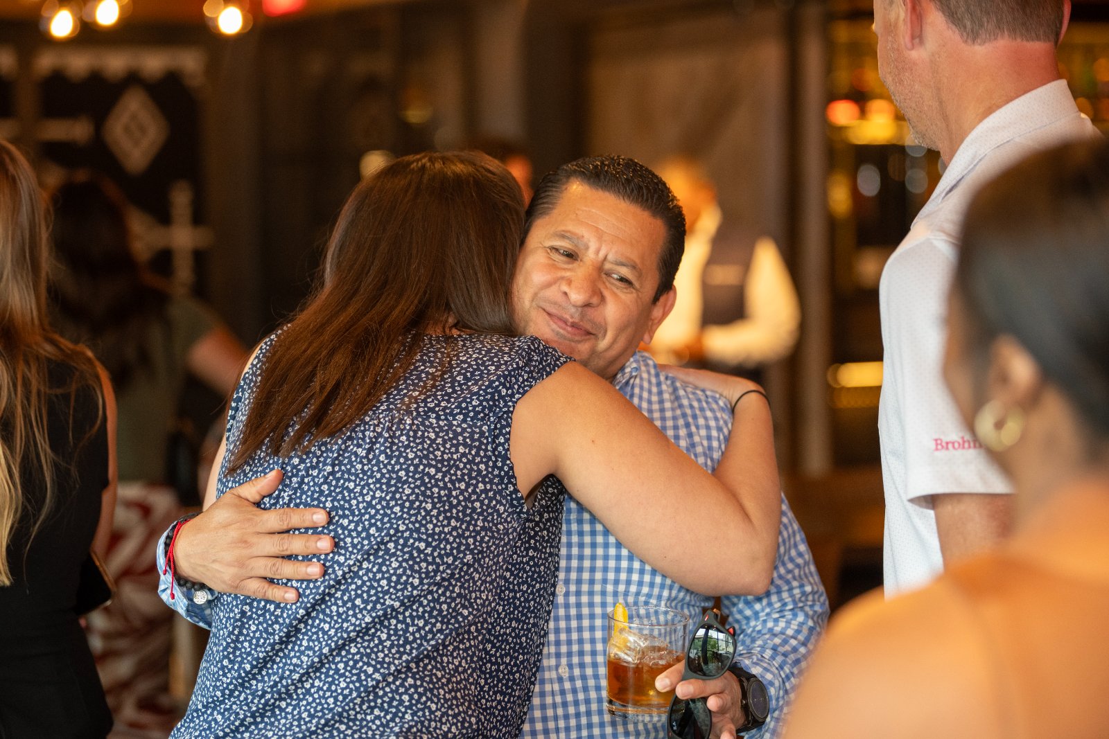 Guests sharing a warm greeting during the Brohan Real Estate event at Haywire, captured in a lively social atmosphere — photographed by Zan Visuals.