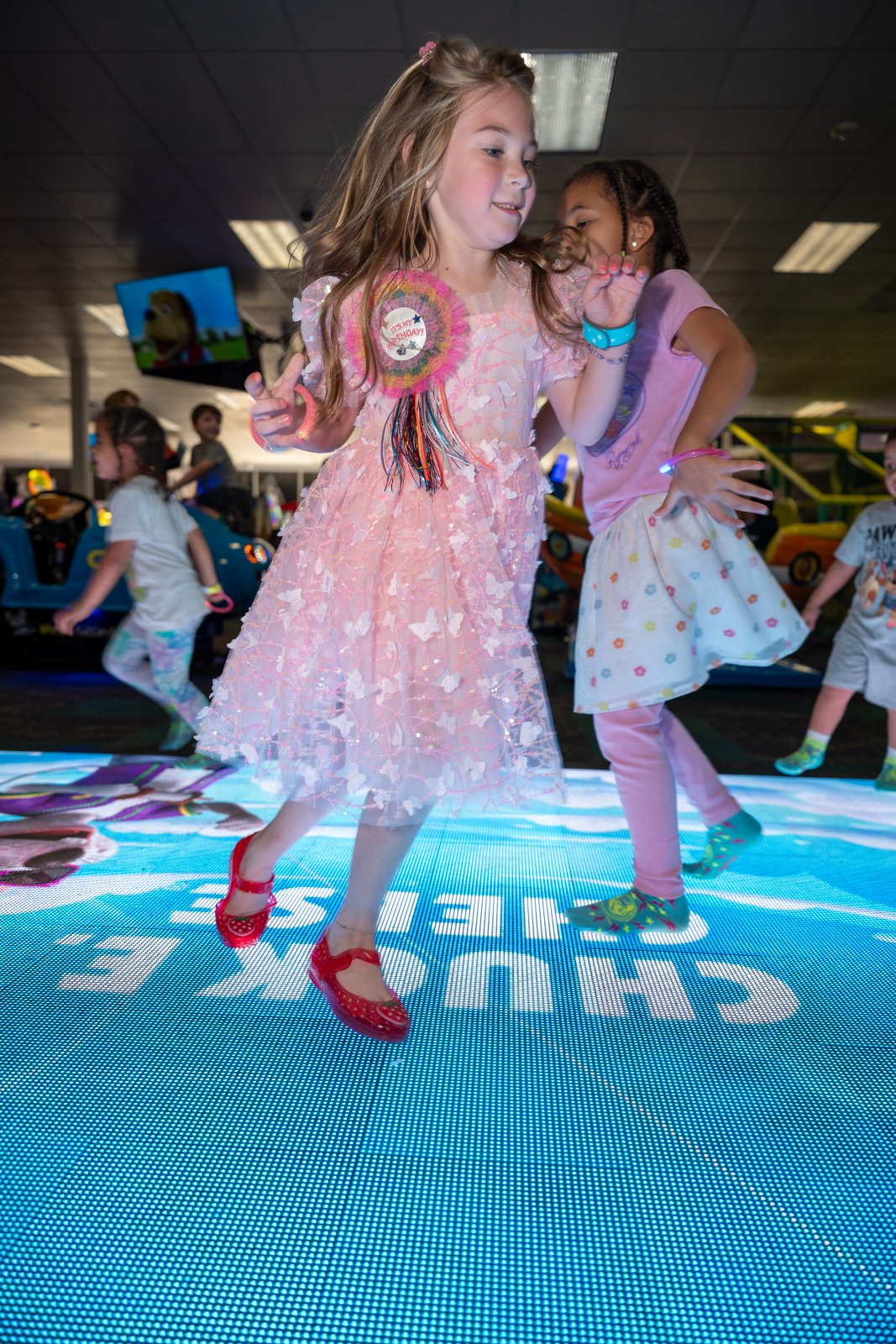 Children dancing and celebrating on an illuminated floor during a birthday event at an indoor entertainment venue — photographed by Zan Visuals.
