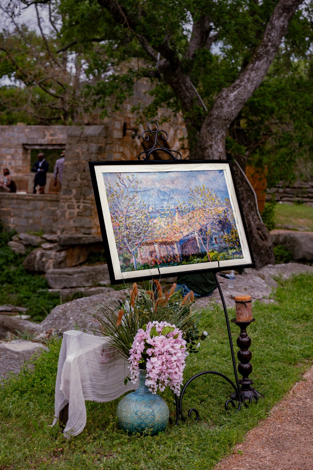 Artistic outdoor wedding ceremony decor displayed on an easel, photographed by Zan Visuals, an Austin wedding photographer.