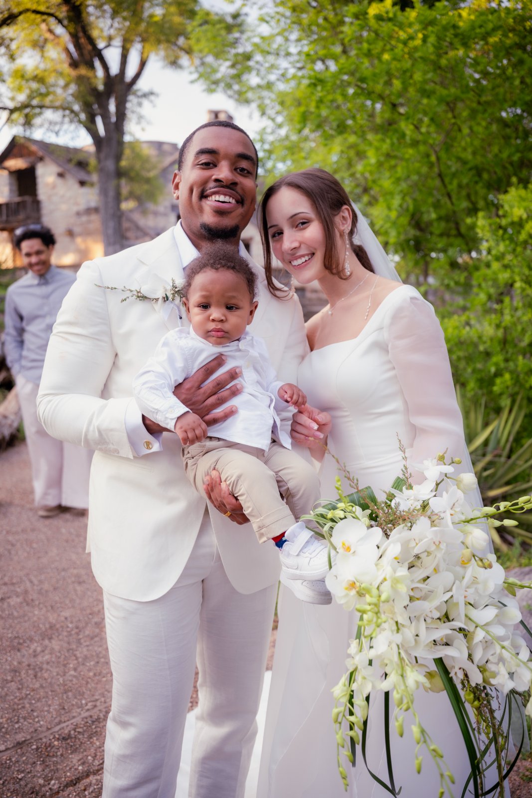 A bride, groom, and child sharing a joyful moment during an outdoor wedding, photographed by Zan Visuals in Austin, Texas.