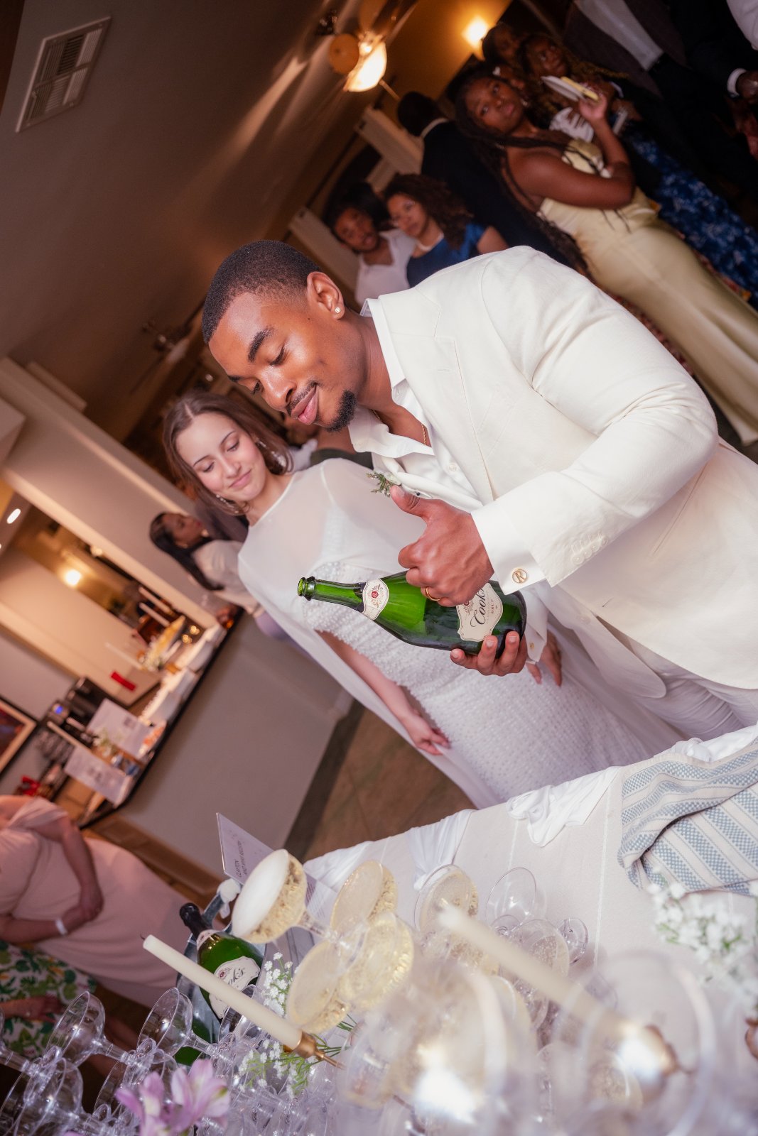 A groom pouring champagne over a stacked glass tower during a lively wedding reception, photographed by Zan Visuals in Austin, Texas.