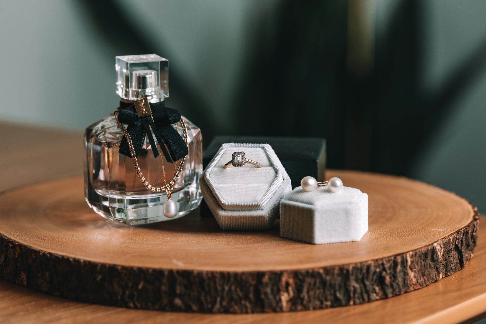 Elegant wedding detail flatlay featuring a perfume bottle, diamond ring in a velvet box, and pearl earrings, captured by Zan Visuals.